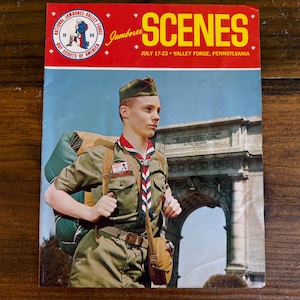 May include: A vintage magazine cover titled "SCENES" from the National Jamboree, Valley Forge, Pennsylvania, July 17-23, 1964. The cover features a young Boy Scout in uniform with a backpack, standing in front of an archway.