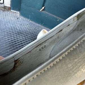 Pu&ograve; includere: Primo piano dell'interno di una scarpa di pelle bianca con la taglia 4 1/2 B stampata sulla soletta.