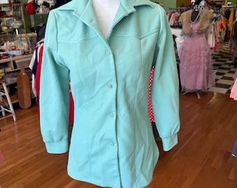 May include: A light turquoise button-down shirt with long sleeves and a pointed collar. The shirt is displayed on a mannequin and features a fitted silhouette with vertical seam detailing. The fabric has a subtle ribbed texture, and the buttons are a matching color.