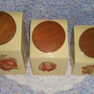 Peut inclure: Ensemble de trois pots en c&eacute;ramique avec couvercles en bois. Chaque pot pr&eacute;sente un motif de fruit diff&eacute;rent&nbsp;: des pommes, des poires et des raisins. Les pots sont de couleur jaune p&acirc;le.
