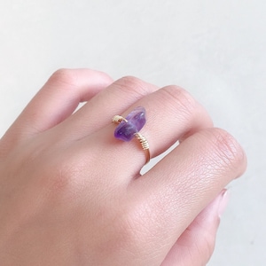 May include: A gold wire ring with a purple amethyst stone wrapped in the wire.