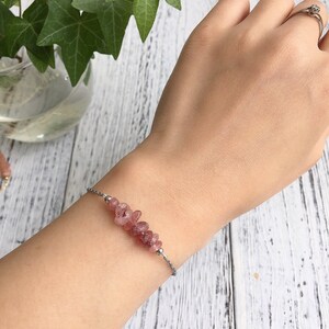 May include: A delicate bracelet with a silver chain and a row of small, pink, irregular-shaped gemstones.