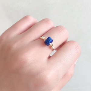 May include: A gold wire wrapped ring with a blue lapis lazuli stone.