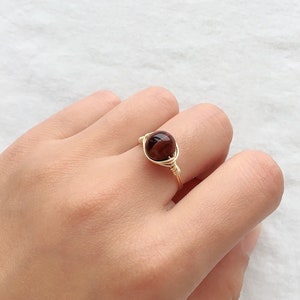 May include: A gold wire wrapped ring with a red tiger's eye stone.