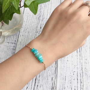 Può includere: Un delicato braccialetto a catena dorata con una fila di perline di pietre preziose blu chiaro e verde.