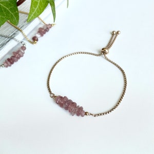 May include: A delicate adjustable bracelet with a silver chain and a cluster of light purple gemstone beads.