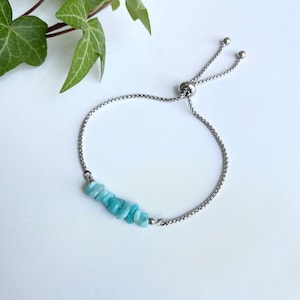 Op de afbeelding: Een zilveren kettingarmband met een turquoise edelsteen bedel. De armband heeft een verstelbare schuifsluiting.