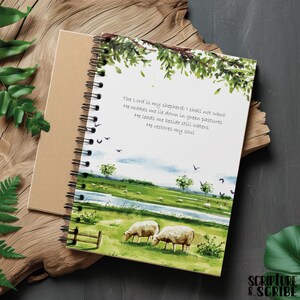 May include: A spiral bound journal featuring a watercolour illustration of a green meadow with a river, two sheep, and a quote from Psalm 23: "The Lord is my shepherd; I shall not want. He makes me lie down in green pastures. He leads me beside still waters. He restores my soul."