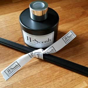 May include: Black diffuser bottle with a silver lid and black reeds. The bottle has a white label that says "JT-Scents Handmade in Scotland".