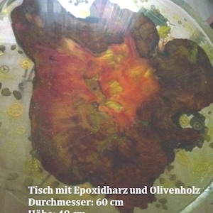 Könnte beinhalten: Ein runder Tisch mit Holzkern in klarem Epoxidharz. Der Tisch hat einen Durchmesser von 60 cm, eine Höhe von 48 cm und eine Stärke von 6 cm. Der Tisch hat ein natürliches Holzmaserungsmuster. Der Tisch ist aus Olivenholz.