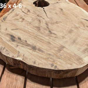 Pode incluir: Uma laje de madeira natural com borda viva, medindo aproximadamente 102 x 91 x 10-15 cm. A superfície castanho-clara exibe padrões de grão de madeira e um nó. A laje provavelmente se destina ao uso como mesa ou elemento decorativo.
