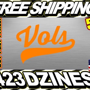 May include: Orange vinyl decal with the word "Vols" in a stylized font. The decal is 5 inches tall and includes the text "BUY 1 GET 1 FREE!" and "423 DZINES".