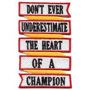 May include: Five white fabric patches with red and yellow borders. The patches are stacked vertically and read "Don't Ever Underestimate The Heart Of A Champion".