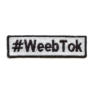 May include: A white and silver embroidered patch with black text that reads "#WeebTok".