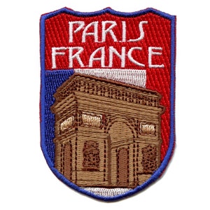 May include: Embroidered patch with a red, white, and blue shield design. The shield features the text "PARIS FRANCE" and an embroidered image of the Arc de Triomphe.