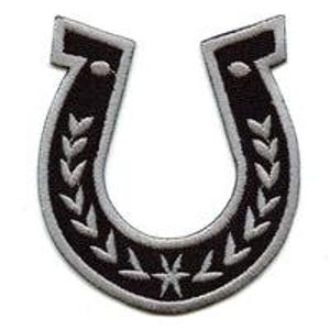 May include: Black and white embroidered horseshoe patch. The patch features a black horseshoe shape with a white border and detailed white leaf and star designs. The horseshoe is a symbol of good luck.