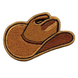Pode incluir: Um patch de chapéu de cowboy marrom com um design bordado detalhado. O patch apresenta a forma clássica de um chapéu de cowboy com uma aparência texturizada e um contorno marrom escuro. A aba e a copa do chapéu são claramente definidas.