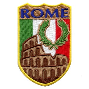 May include: An embroidered patch with a yellow border, depicting the Colosseum in Rome, Italy. The patch features the Italian flag colors of green, white, and red, with a laurel wreath in the center. The word "ROME" is embroidered in blue letters at the top of the patch.