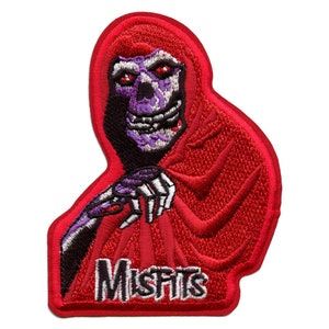 Op de afbeelding: Rode geborduurde patch met een paars en zwart skelet in een rode kapmantel met het woord "Misfits" in witte letters.