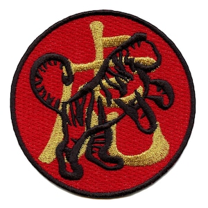 May include: A red circular embroidered patch with a black tiger and gold Chinese character for "tiger" in the centre.