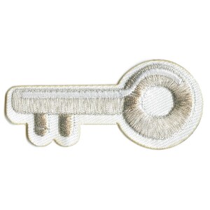 May include: Embroidered key patch with a white border and a metallic silver key design. The key has a detailed, textured appearance, suitable for adding to clothing or accessories.