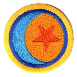 Pode incluir: Remendo bordado circular com uma estrela laranja no centro sobre um fundo laranja. Uma lua crescente azul e uma borda amarela e azul circundam a estrela. O remendo tem uma aparência texturizada.