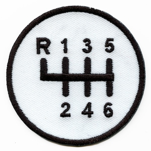 Op de afbeelding: Witte ronde patch met een zwarte omtrek en een zwart schakelpatroon. Het patroon bevat de nummers 1, 2, 3, 4, 5, 6 en de letter R.