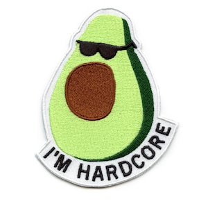 Pode incluir: Um abacate verde com um caroço marrom usando óculos de sol e uma borda branca com o texto "I'm Hardcore" em preto.