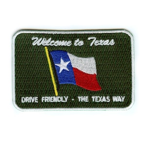 May include: Green embroidered patch with white stitching. The patch features a waving Texas flag with a white star and the text "Welcome to Texas" and "Drive Friendly - The Texas Way".