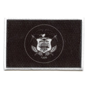 May include: Black and white embroidered patch featuring the state seal of Utah. The seal depicts a shield with a beehive, a mountain range, and the words "Industry" and "Utah". The year "1896" is displayed below the shield.