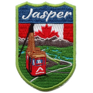 May include: Embroidered patch with a green border, featuring a red cable car with a brown roof, a Canadian flag with a red maple leaf, and the text "Jasper" in white cursive lettering.