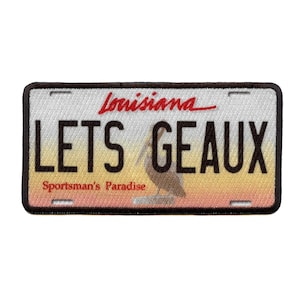 May include: A white and yellow Louisiana license plate patch with black text that reads "LETS Geaux" and "Sportsman's Paradise". The patch features a pelican in the center.