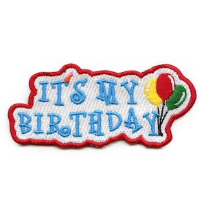 May include: A white and blue embroidered patch with the text "It's My Birthday" in blue lettering. The patch has a red border and features three colorful balloons.