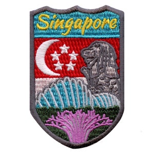 Op de afbeelding: Een grijs geborduurd patch in de vorm van een schild. De patch toont de vlag van Singapore, een leeuwenkop en een bloem. De tekst "Singapore" is in het geel geborduurd bovenaan de patch.