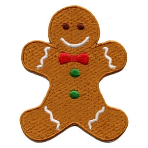 May include: A gingerbread man embroidered patch with a red bow tie and green buttons. The patch is brown with white icing details.