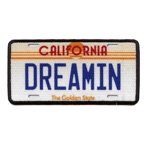 May include: Embroidered patch in the style of a California license plate. It reads "DREAMIN" in blue, with "CALIFORNIA" in red above and "The Golden State" below. The background is white with orange stripes and a black border.