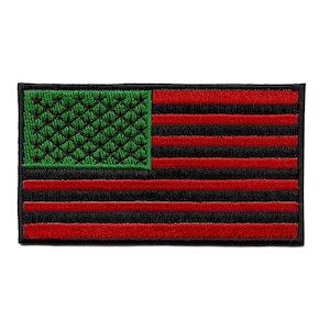 Puede incluir: Una bandera americana negra y roja con una esquina superior izquierda verde. La bandera está bordada y tiene una superficie texturizada.