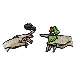 May include: Embroidered patches showing hands, one holding a lit cigarette with smoke, the other holding a green lighter with a flame. The patches have a beige background and black outlines.