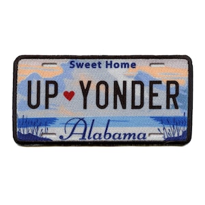 May include: A blue and white patch with a black border. The patch has a sunset scene with the text "Sweet Home" and "UP ♥ YONDER" in black. The text "Alabama" is in black at the bottom of the patch.