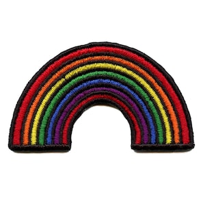 Puede incluir: Un parche bordado en forma de arcoíris. El parche tiene un contorno negro y está hecho de hilo de colores.