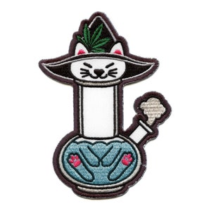 May include: Embroidered patch of a white cat wearing a green and black witch hat, holding a blue bong with pink paw prints. The bong has a white stem and a gray smoke plume.