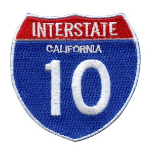May include: Embroidered patch of the Interstate 10 highway sign for California. The patch has a blue centre with the number 10 in white, a red top section with the word "INTERSTATE", and the word "CALIFORNIA".