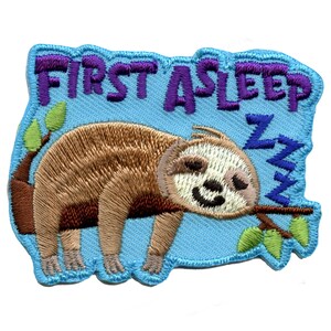 May include: An embroidered patch featuring a cartoon sloth sleeping on a branch. The patch is blue with green leaves and the text "FIRST ASLEEP" in purple.