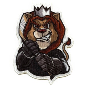 May include: Embroidered patch featuring a cartoon lion wearing a crown and holding a hockey stick. The lion has a fierce expression and is wearing a black jersey. The patch is white with a gold outline.