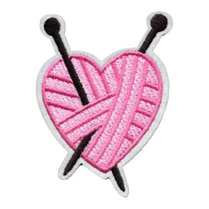 May include: Pink yarn in the shape of a heart with two black knitting needles crossing through it.