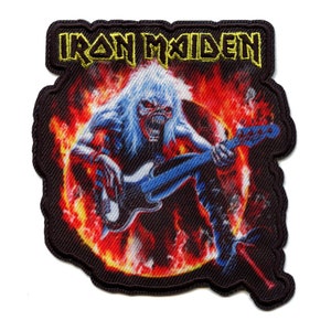 May include: Iron Maiden band patch with a black background and a fiery orange and red ring around a blue and white electric guitar being played by a skeleton figure with a white skull and a screaming mouth. The band name "Iron Maiden" is written in yellow letters at the top of the patch.