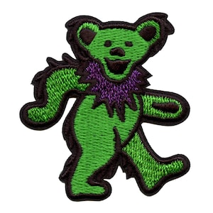 Puede incluir: Parche bordado con un oso bailarín verde con un cuello morado y contorno marrón. El oso está en posición de caminar, con los brazos y las piernas extendidos. Adecuado para ropa o accesorios.