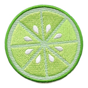 May include: A green embroidered patch of a lime wedge with white seeds. The lime is cut into six sections.