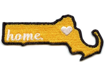 May include: Yellow felt outline of the state of Massachusetts with the word "home" embroidered in white and a white heart in the upper right corner.