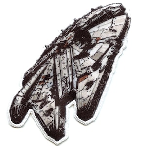 Könnte beinhalten: Ein weißer und brauner Stoff-Patch, der das Raumschiff Millennium Falcon aus Star Wars darstellt. Der Patch hat einen weißen Rand mit einem genähten Saum.